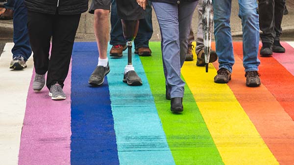 People walking on a road painted like a rainbow