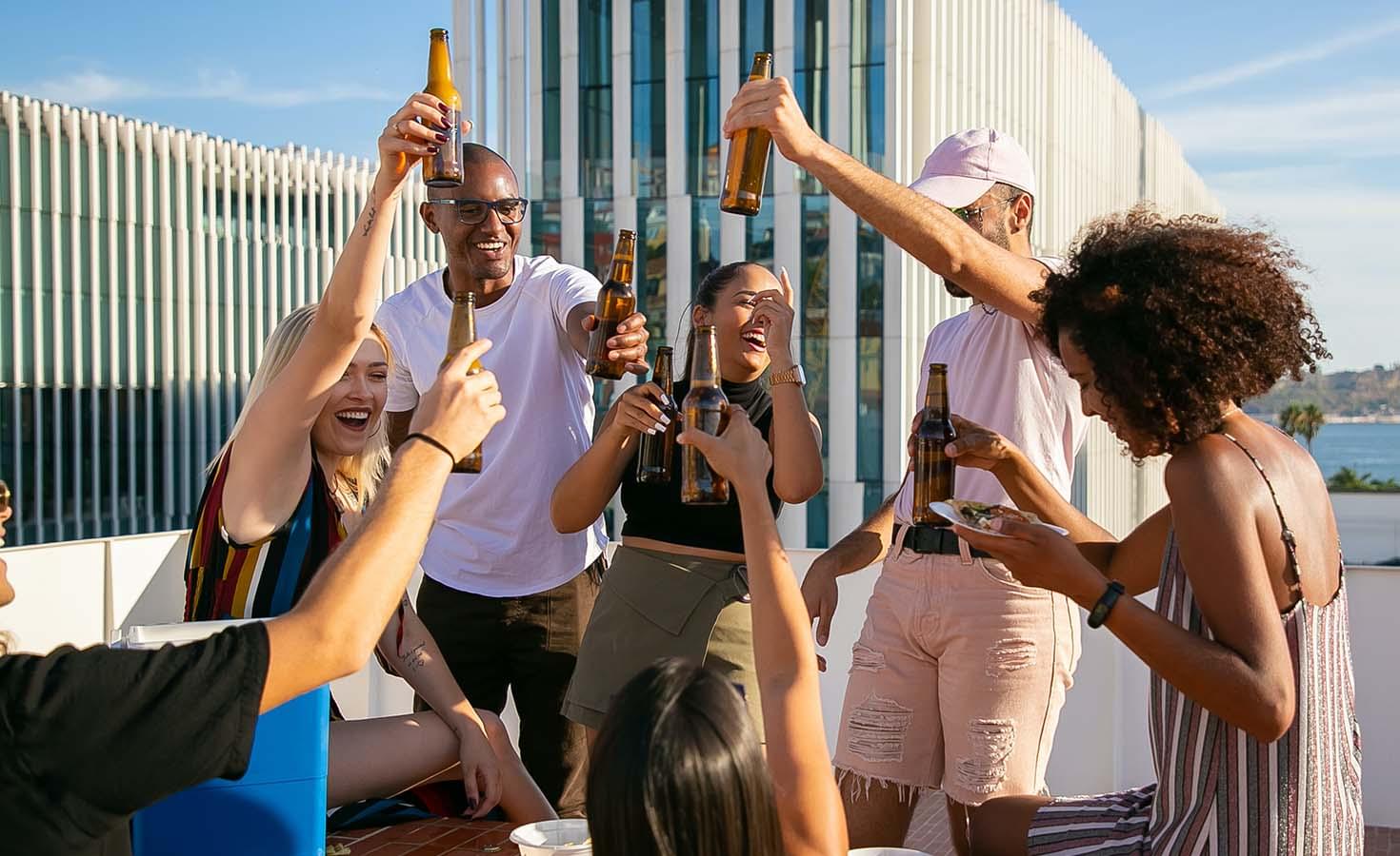 Group of friends celebrating and toasting with beer bottles