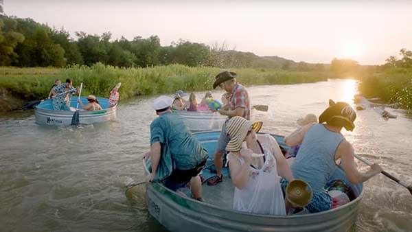 Three groups of people floating down a river in oversized metal tubs