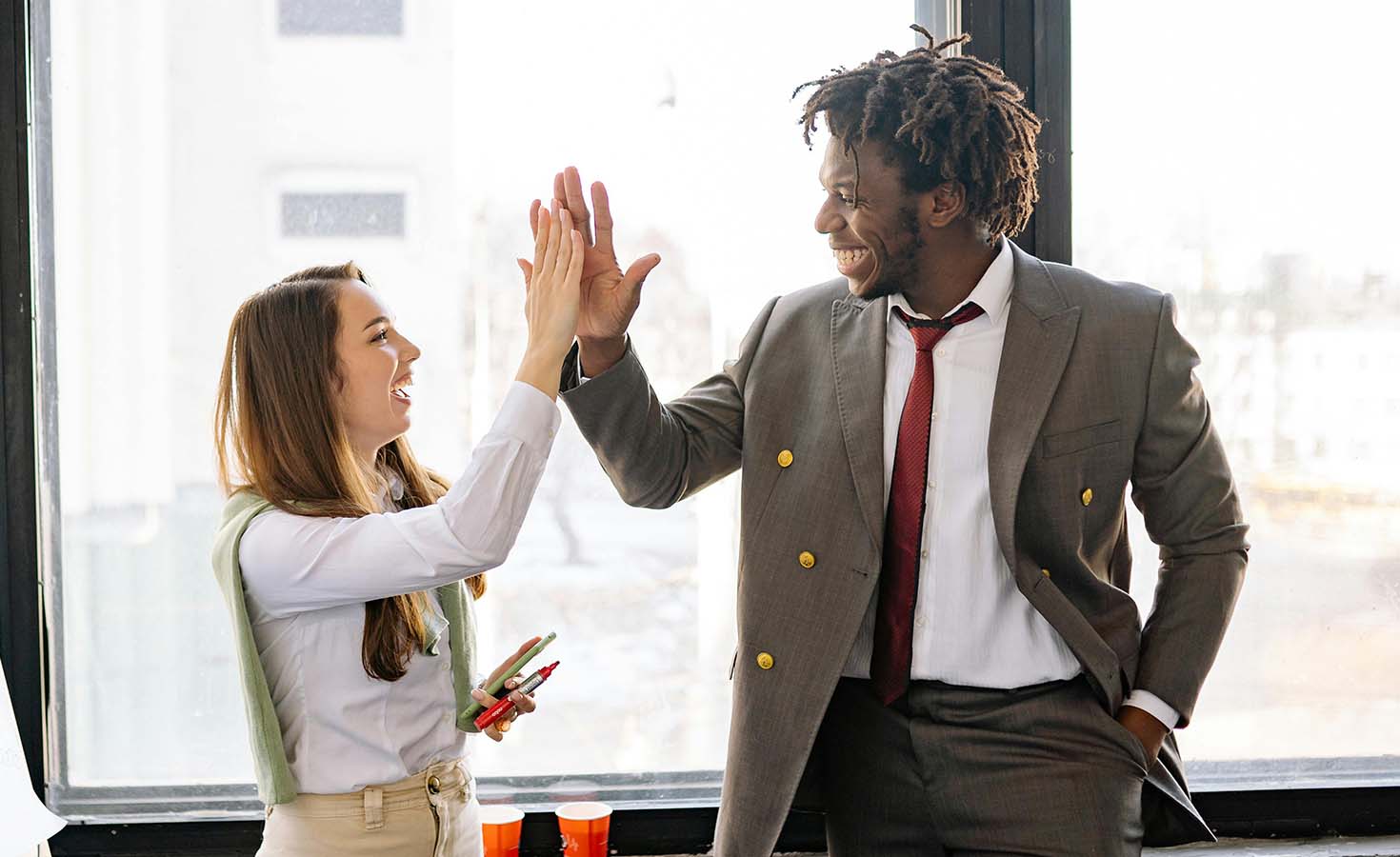 Man and woman in an office giving a high five to each other