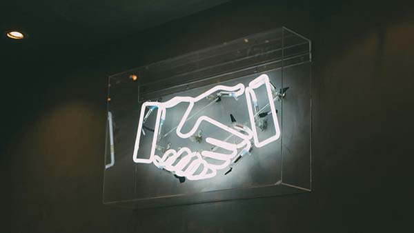 Neon sign of a handshake icon